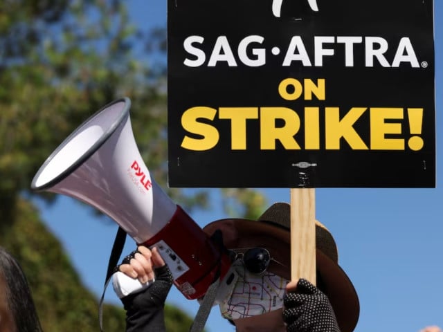 a person holds a sign as sag aftra actors and writers guild of america wga writers walk the picket line during their ongoing strike outside walt disney studios in burbank california us august 22 2023 photo reuters